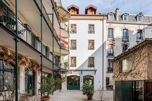 A courtyard with a central building featuring a green door and multiple windows. - La Cour du 6 (Annecy)