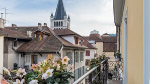 A traditional European town with a prominent church tower, narrow streets, and residential buildings with shutters. - La Cour du 6 (Annecy)
