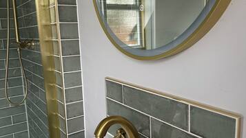 A bathroom with a white sink, gold faucet, and a round mirror with a gold frame.