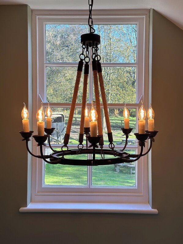 A chandelier with multiple candles in a room with a large window. - Black Horse (Buntingford)