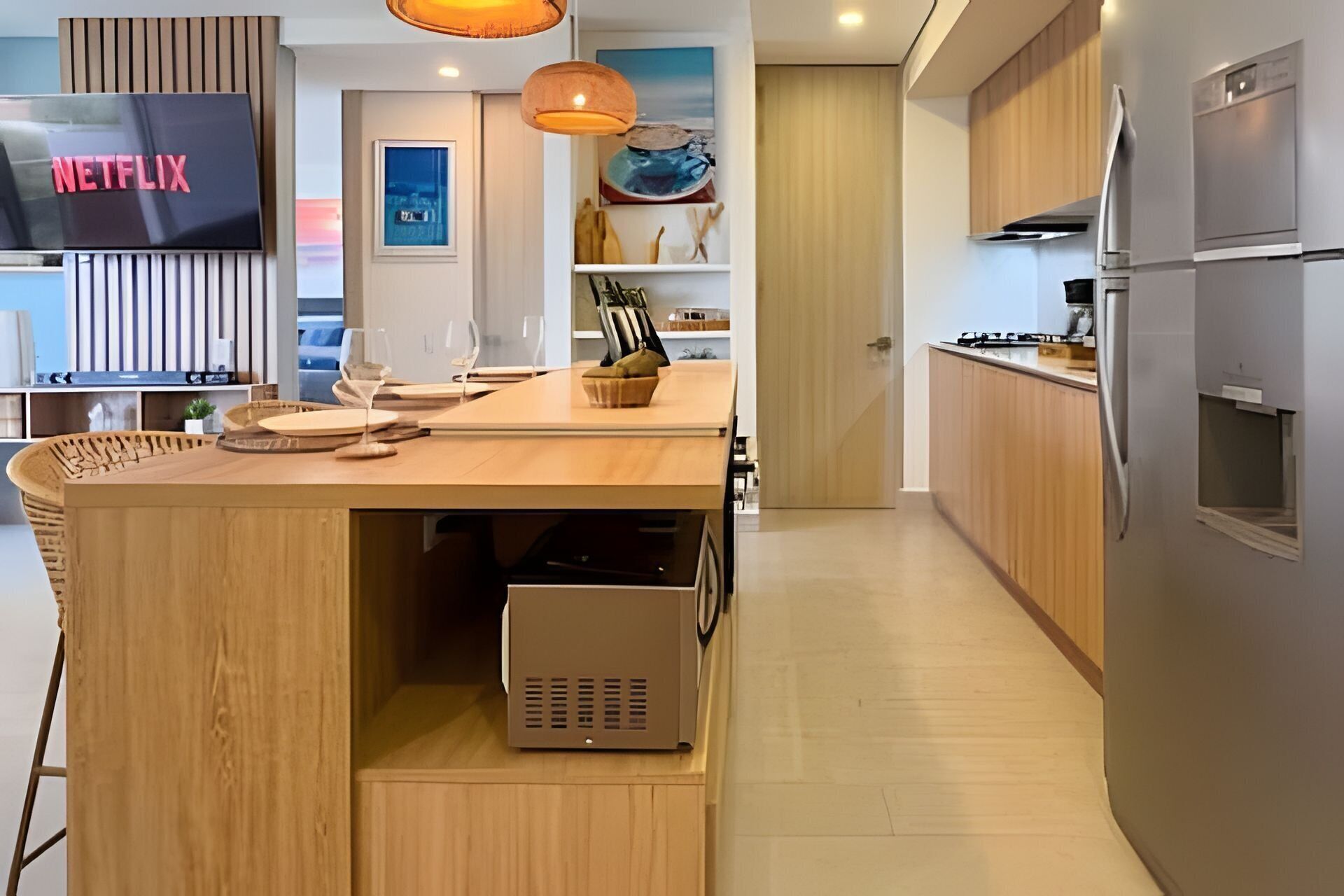 Una cocina moderna con una isla integrada, un televisor de pantalla plana y un refrigerador.