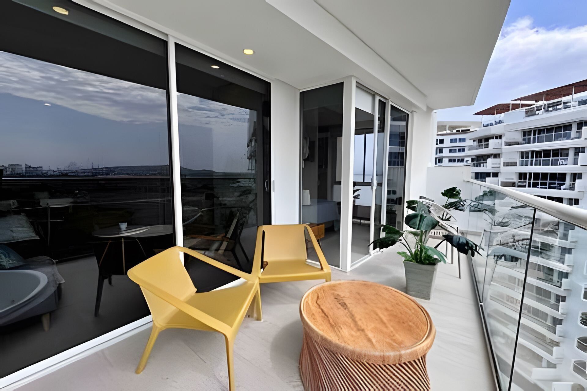 Een balkon met uitzicht op de stad, een zithoek met stoelen en een ronde houten tafel.