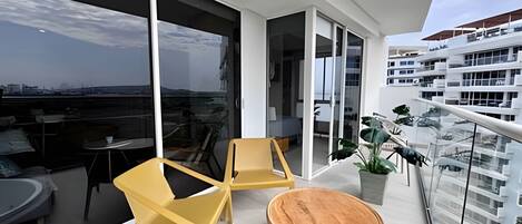 Een balkon met uitzicht op de stad, een zithoek met stoelen en een ronde houten tafel.