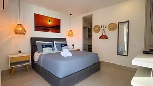 A modern bedroom with a large bed, bedside tables, a wall-mounted painting, and a mirror. - Edificio Martinique  (Cartagena)