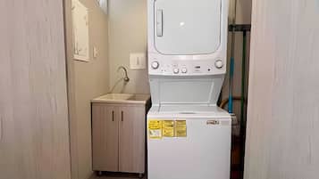 Pequeña lavandería con lavadora, lavabo y armario.