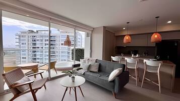Un apartamento moderno con sofá, mesa de comedor, sillas y zona de cocina.