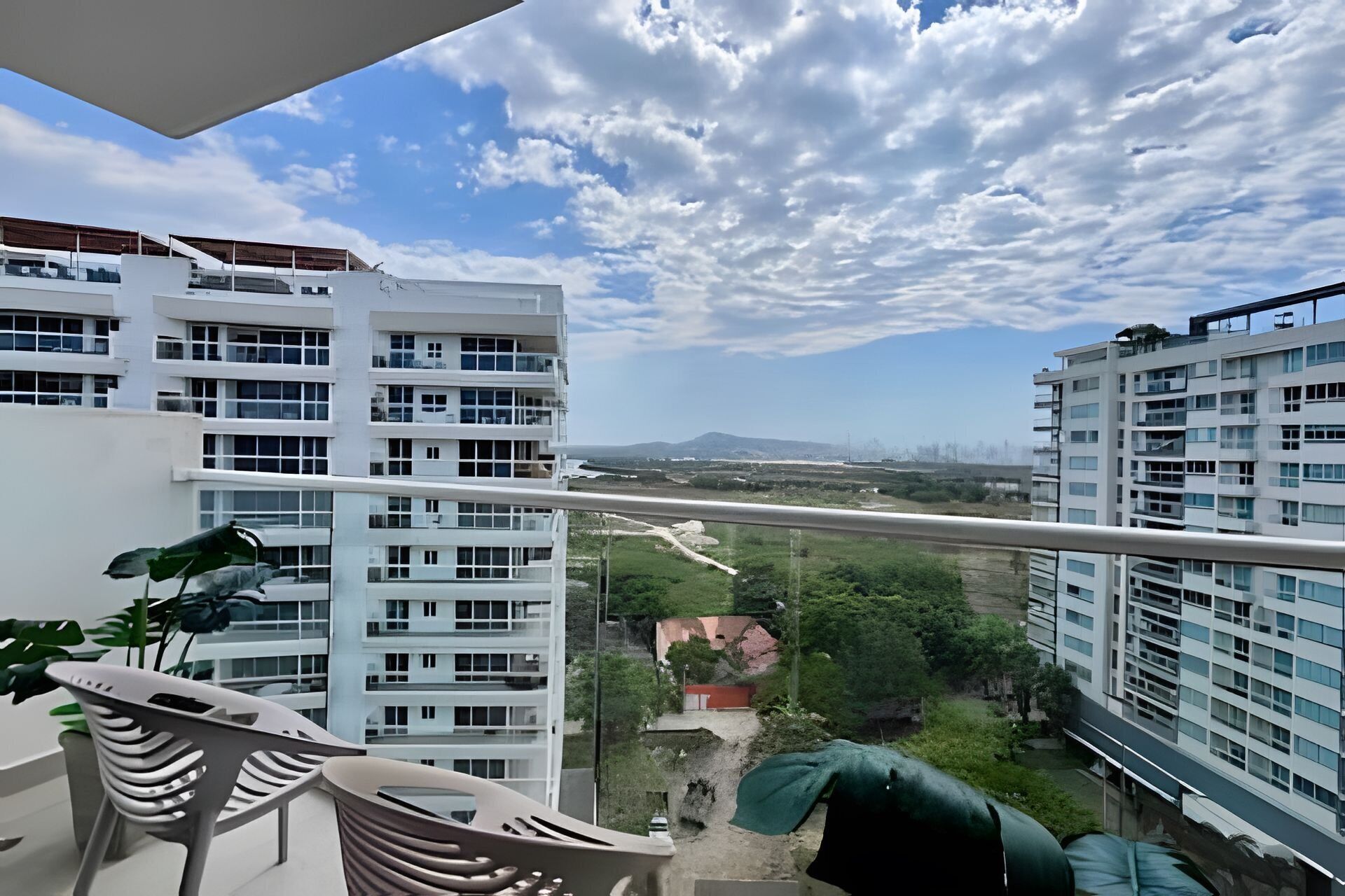 A balcony with a view of adjacent buildings and a distant landscape.