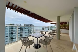 A modern balcony with a table and chairs, a view of high-rise buildings, and a wooden ceiling structure. - Edificio Martinique  (Cartagena)