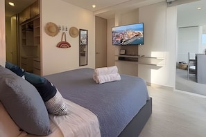 A modern bedroom with a large bed, a television mounted on the wall, and a view of the cityscape. - Edificio Martinique (Cartagena)
