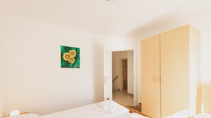 Een hotelkamer met twee bedden, een houten garderobe, een schilderij van zonnebloemen en uitzicht op de gang.