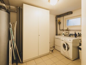 Une buanderie équipée d’un lave-linge, d’un sèche-linge et d’une planche à repasser.