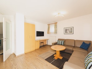 A living room with a sofa, a small table, a TV, and a wardrobe.