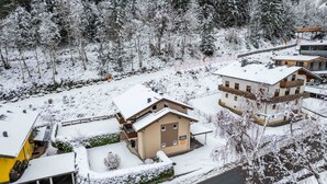 Een besneeuwde bergdorp met chalets, een skipiste en een helder uitzicht op het omliggende bos.