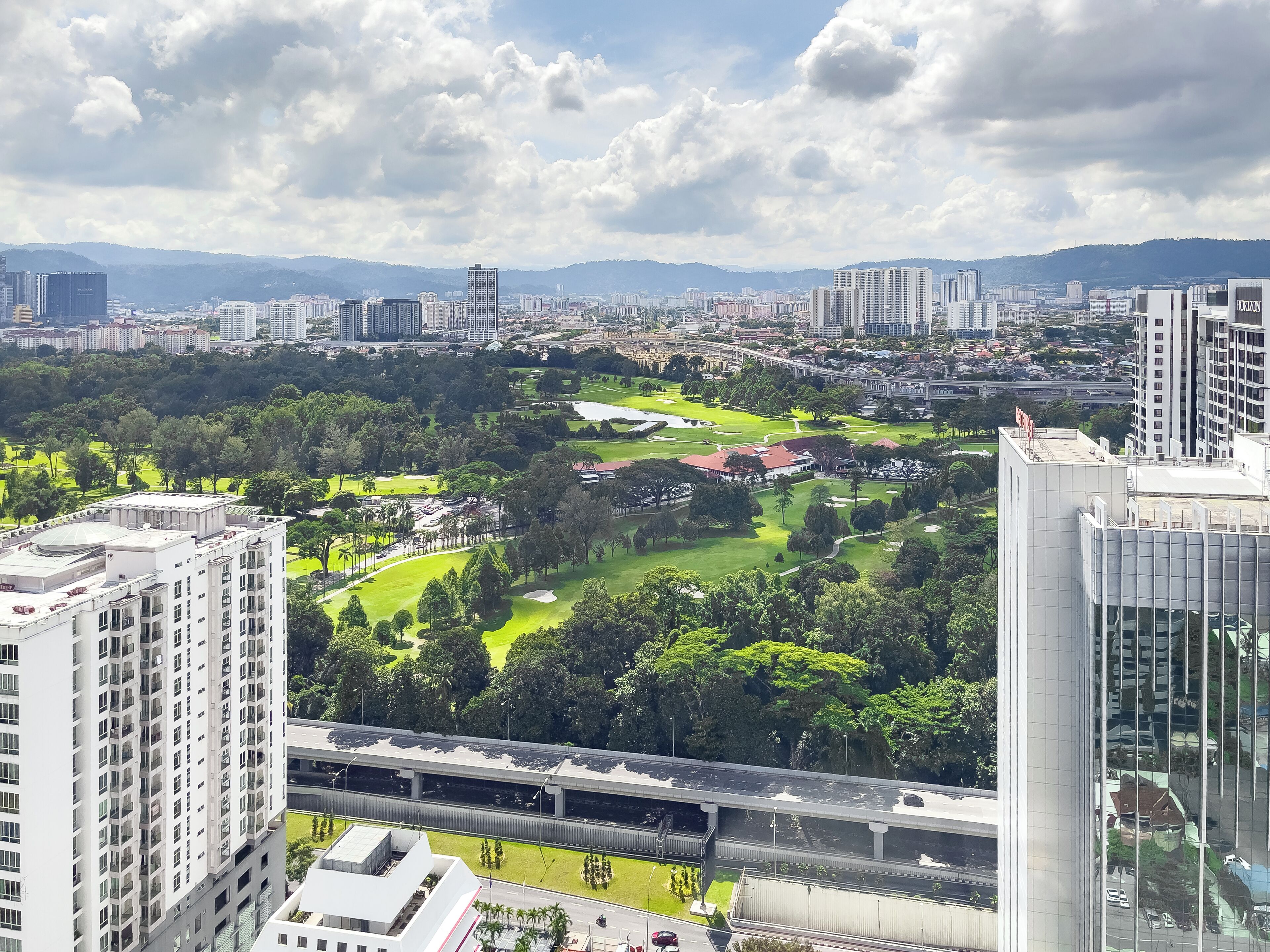 A high-rise building with a view of a golf course and surrounding cityscape.