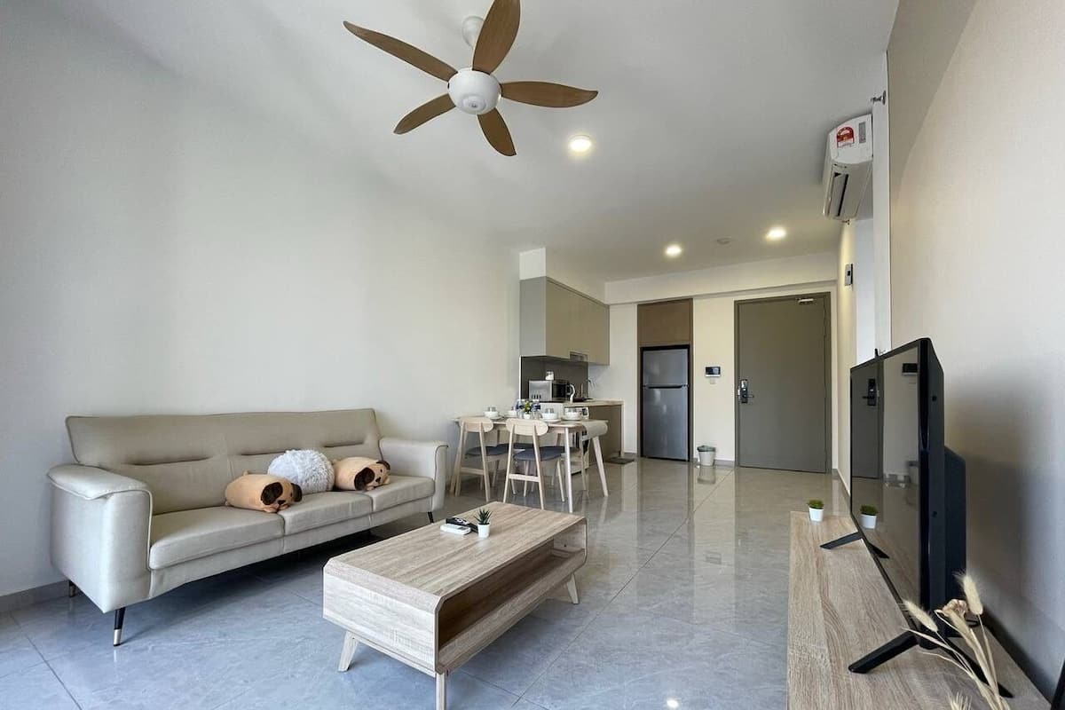 A modern living room with a sofa, coffee table, TV, and ceiling fan.