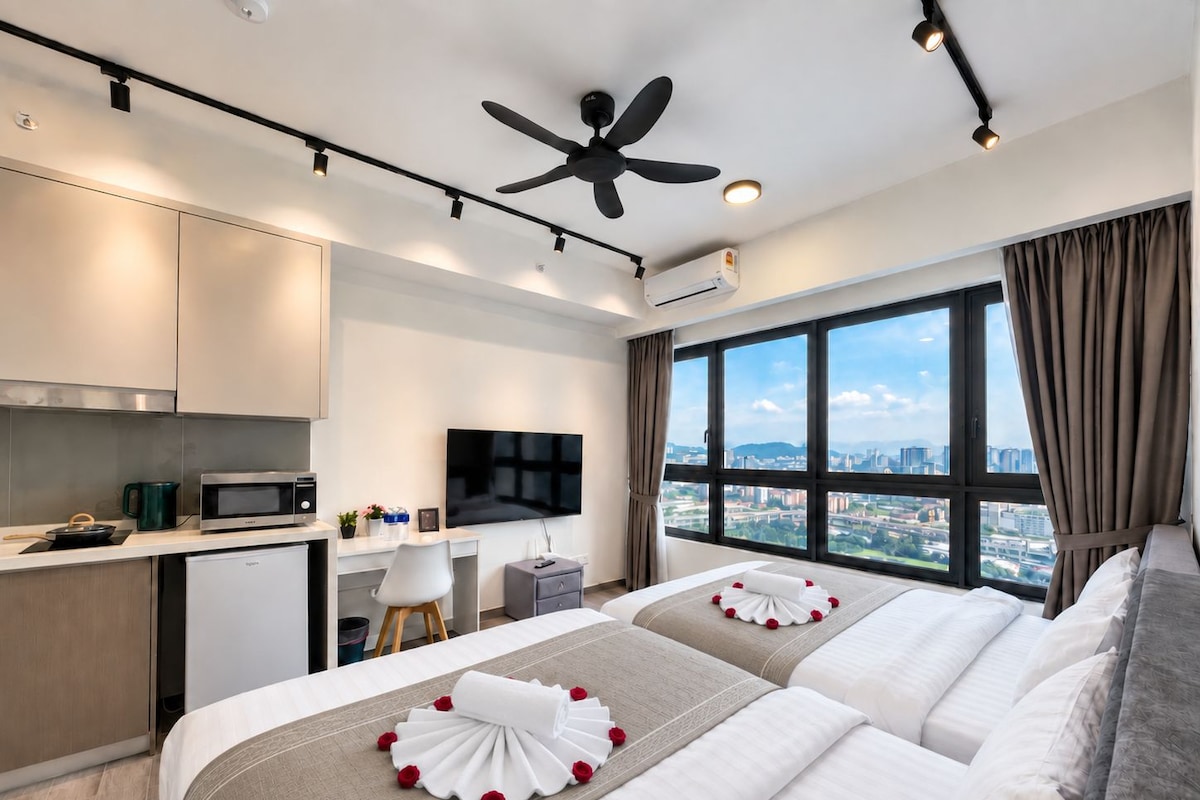 A hotel room with a bed, a desk, a television, and a view of the city.