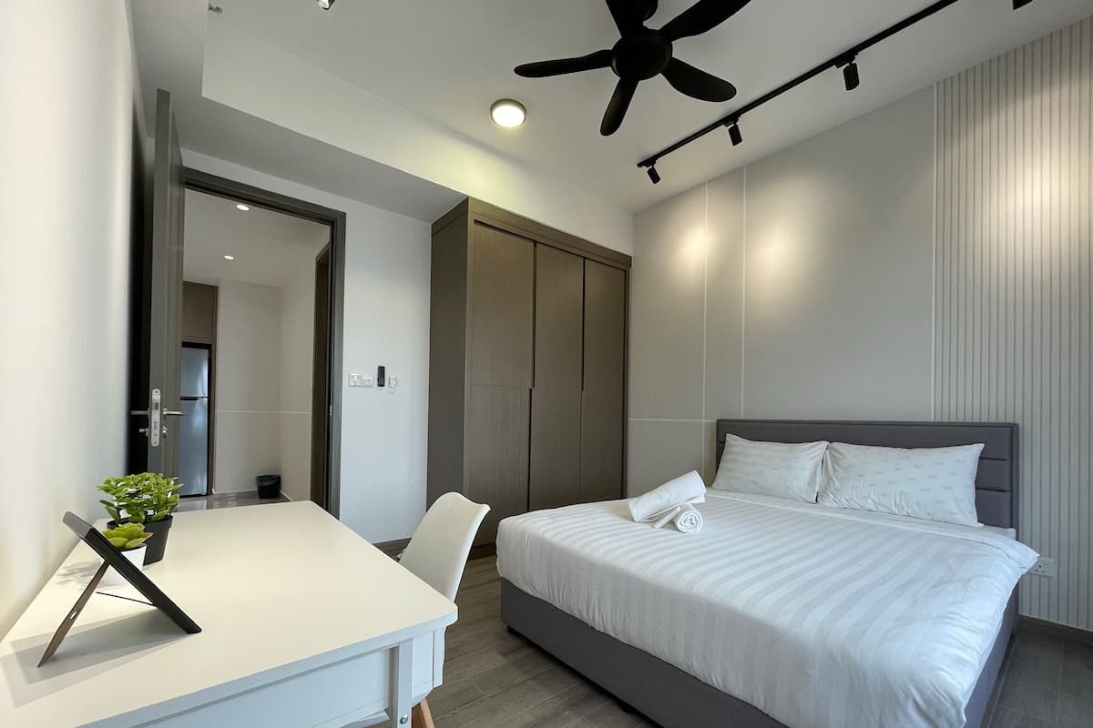 A modern hotel room with a large bed, a desk with a chair, and a ceiling fan.