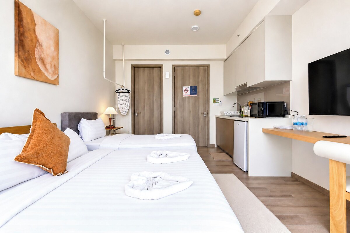 Une chambre d’hôtel équipée d’un lit, d’un bureau, d’une télévision et d’une kitchenette.