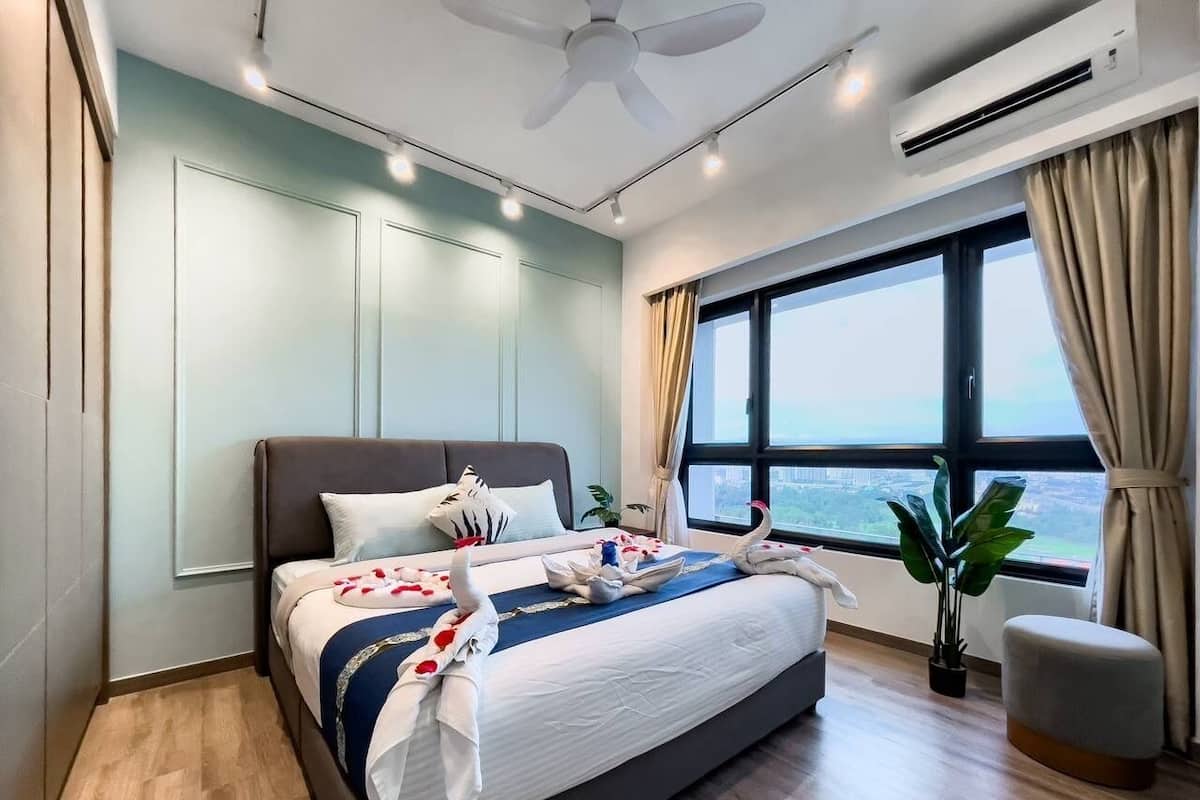 A modern hotel room with a large bed, a ceiling fan, an air conditioning unit, a window with a view, and a small plant.