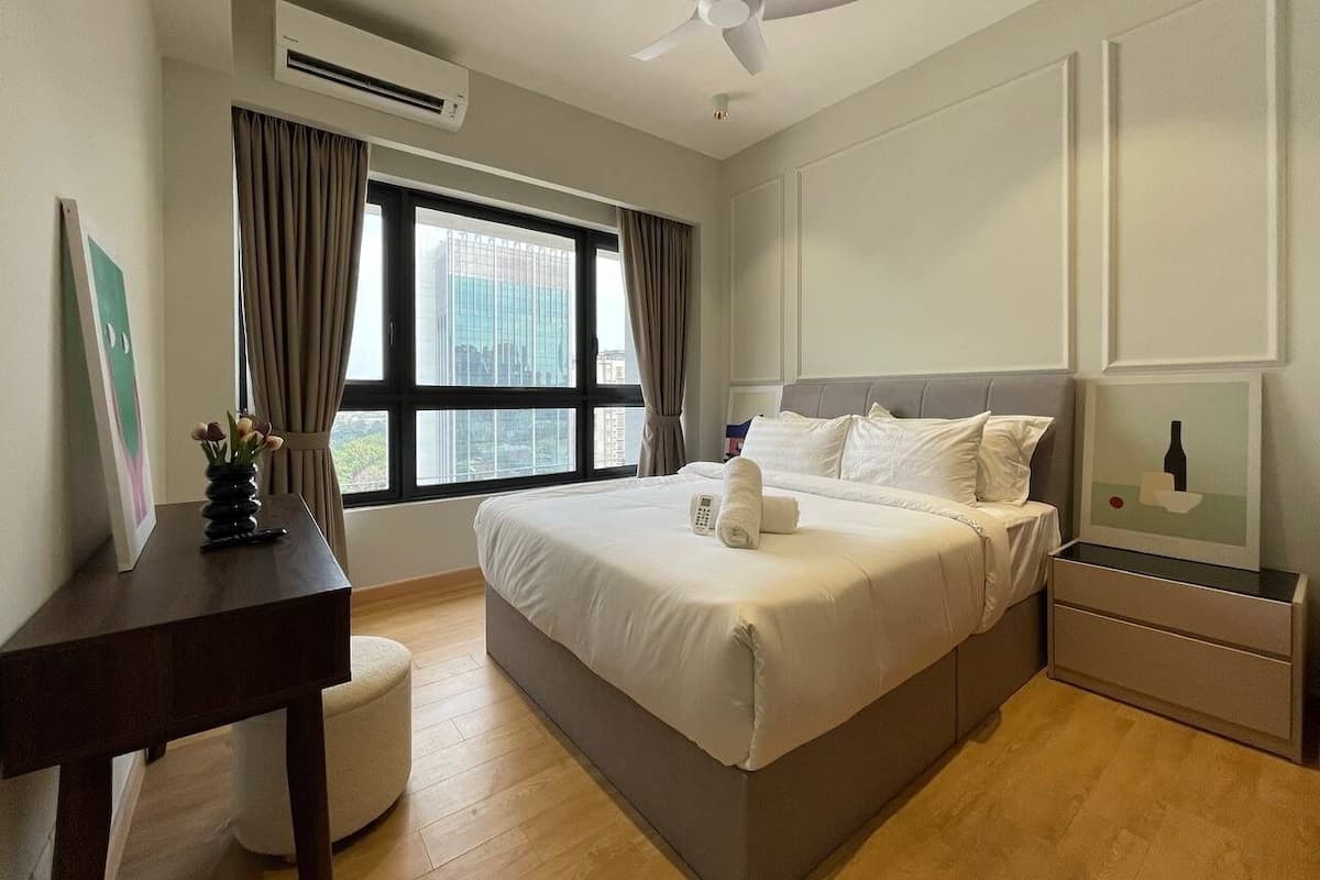 A bedroom with a bed, bedside tables, a desk, a chair, a window with curtains, and a ceiling fan.