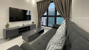 A modern living room with a large flat-screen TV, a sofa, a coffee table, and a TV stand.