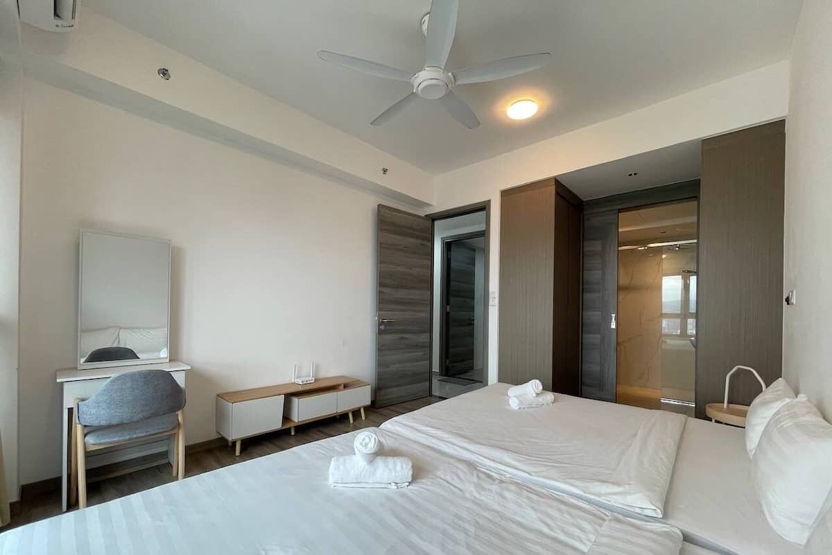 Een moderne hotelkamer met twee bedden, een bureau, een stoel en een plafondventilator.