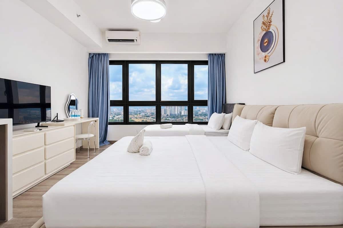 Een hotelkamer met een groot bed, een televisie, een bureau met stoel en een raam met uitzicht op de stad.