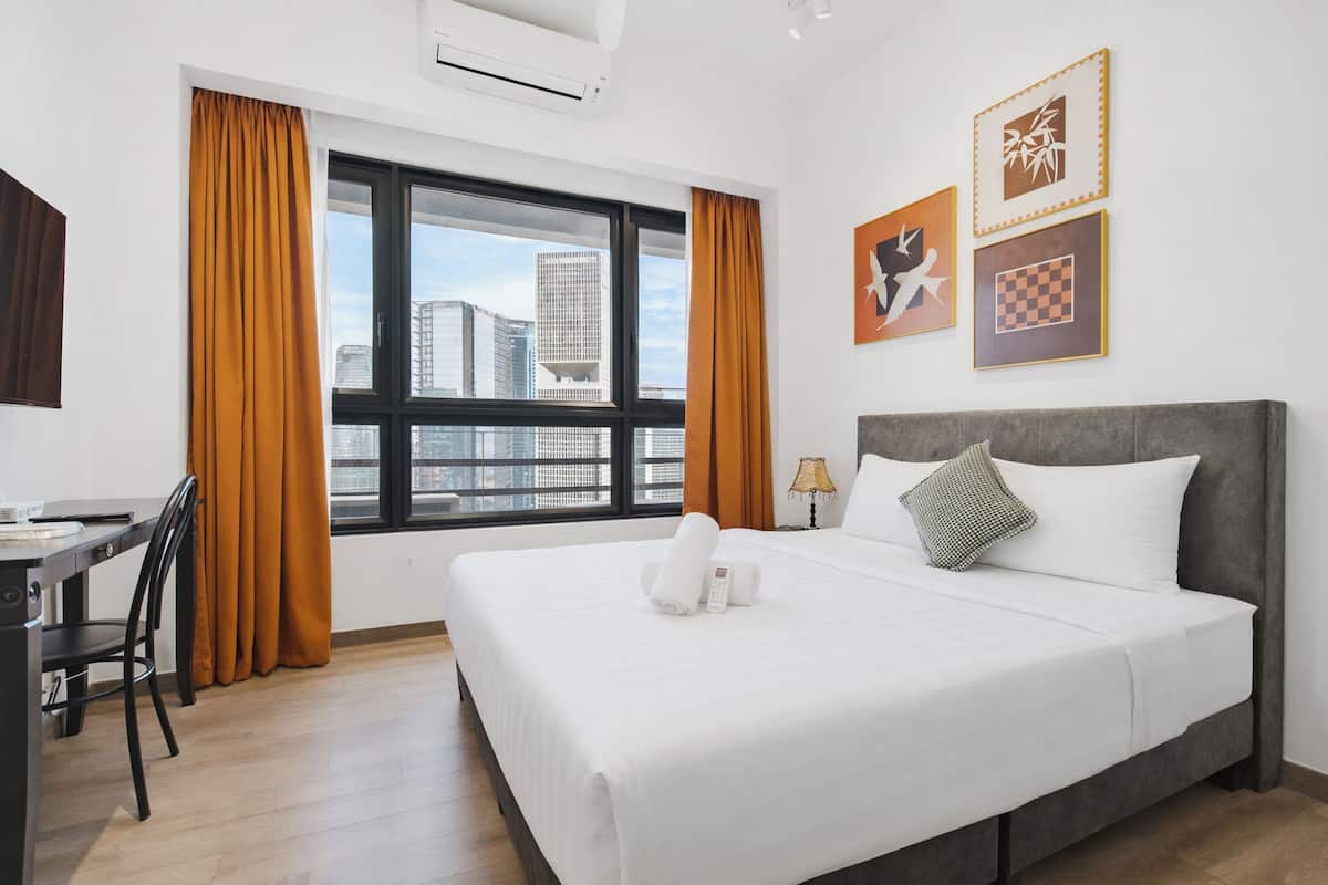 Een hotelkamer met een groot bed, een bureau en een raam met gordijnen.