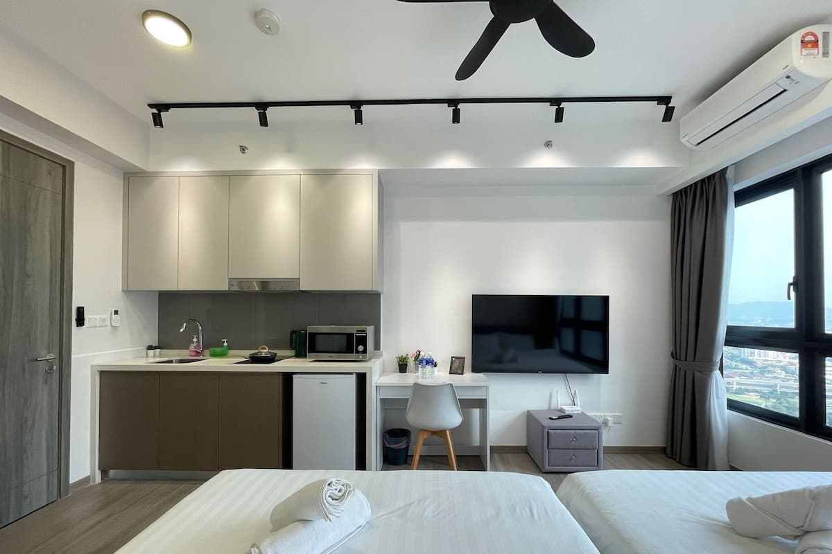 A modern hotel room with a kitchenette, a flat-screen TV, a desk, and two beds.