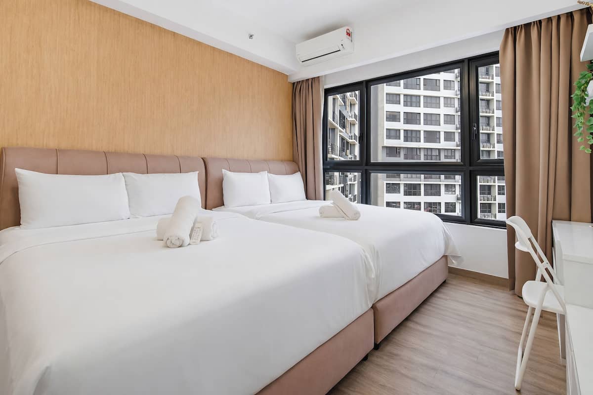 A hotel room with two beds, a desk, and a large window with a view of buildings.