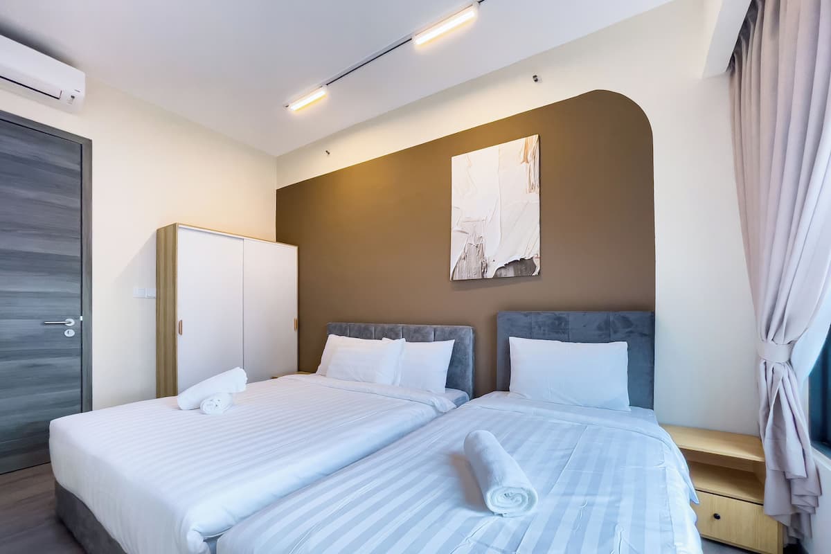 A modern hotel room with two beds, a wardrobe, a painting on the wall, and a window with curtains.
