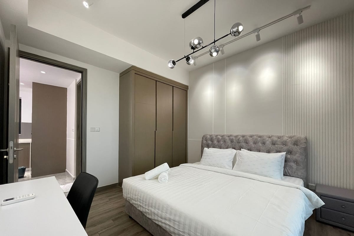A modern hotel room with a bed, a desk, and a wardrobe.