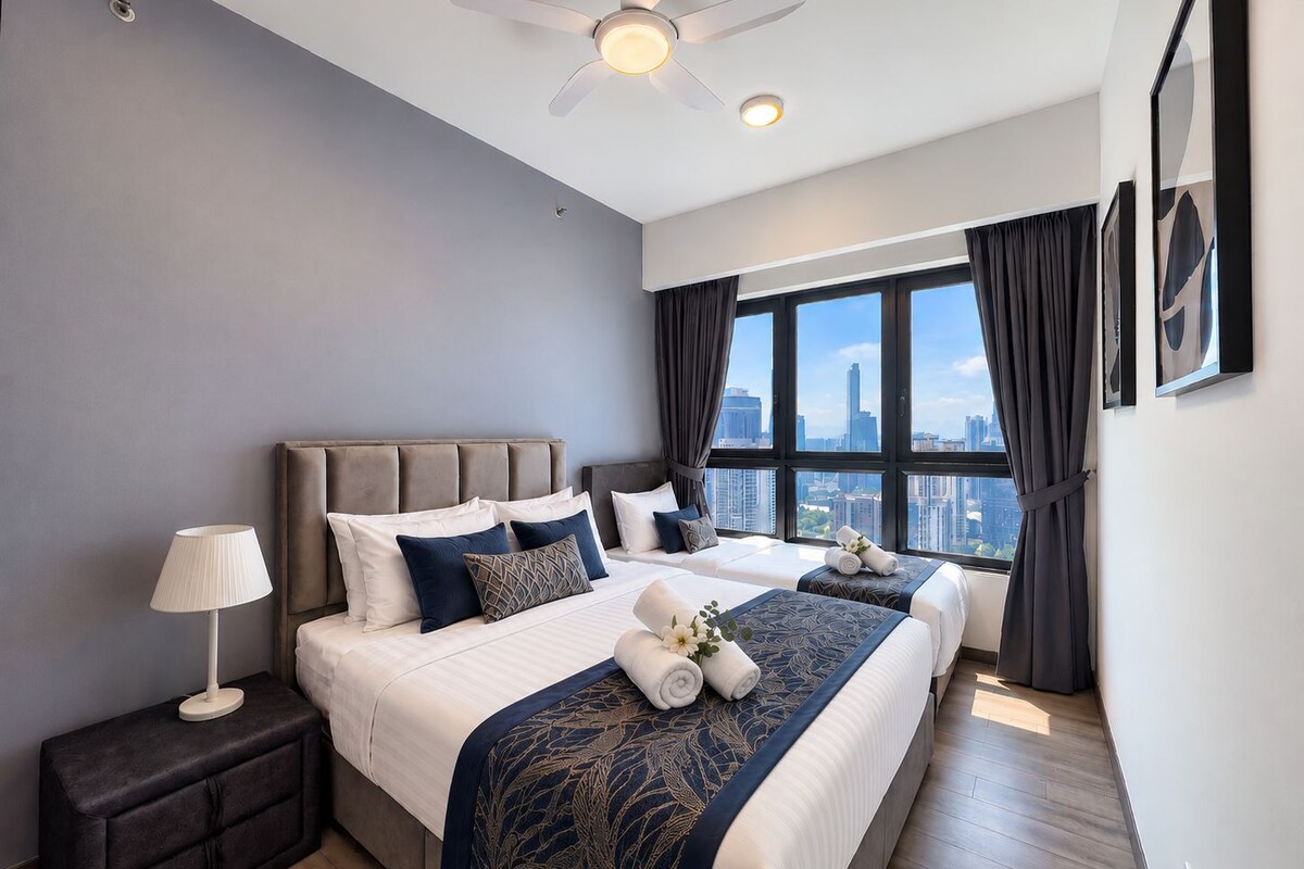 Una habitación de hotel moderna con una cama grande, una mesita de noche, un ventilador de techo y vistas a la ciudad.