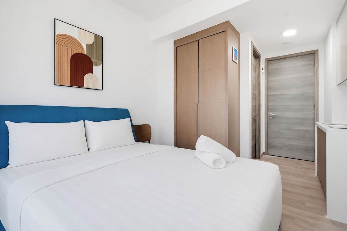 Een hotelkamer met een bed, een kledingkast, een bureau en een kunstwerk aan de muur.