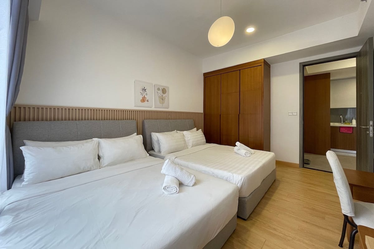 A hotel room with two beds, wooden wardrobe, and a mirror.