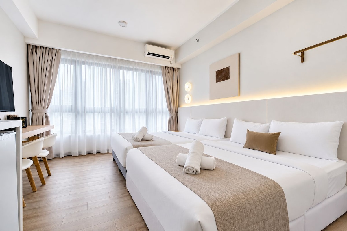A hotel room with a bed, bedside tables, a desk, and a television.
