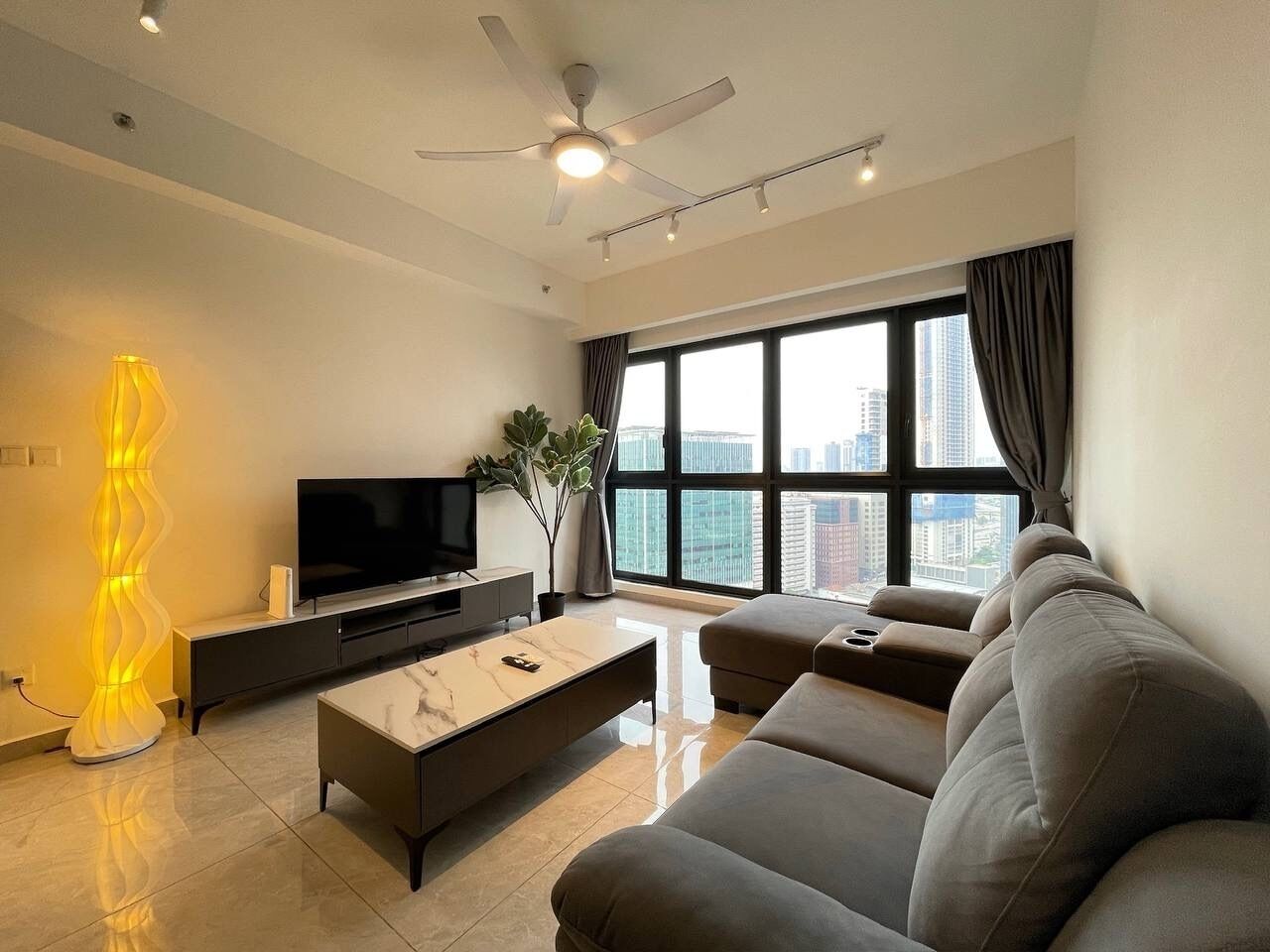 A modern living room with a flat-screen TV, a sofa, a coffee table, and a floor lamp.