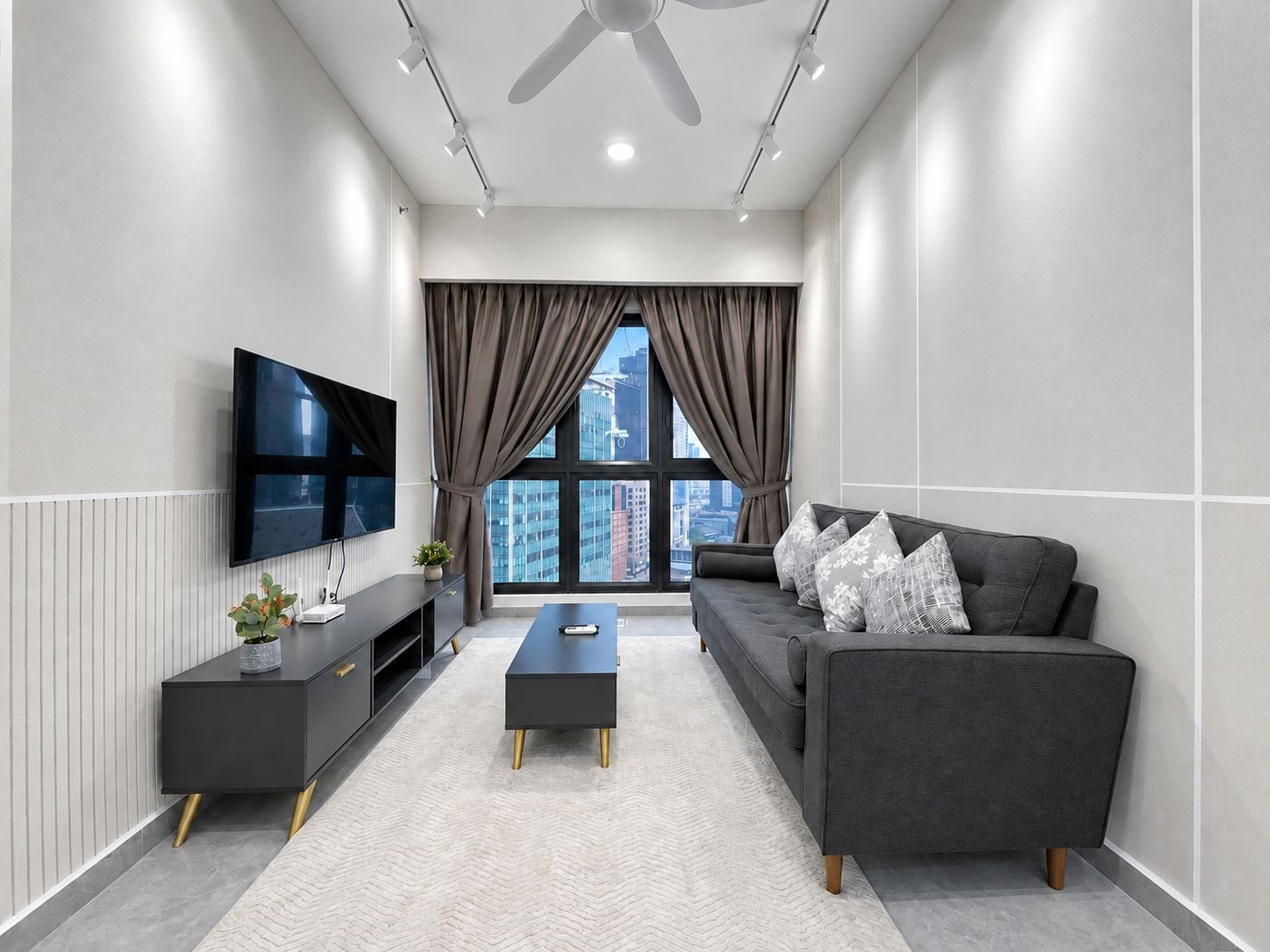 A modern living room with a sofa, coffee table, TV, and a view of the cityscape.