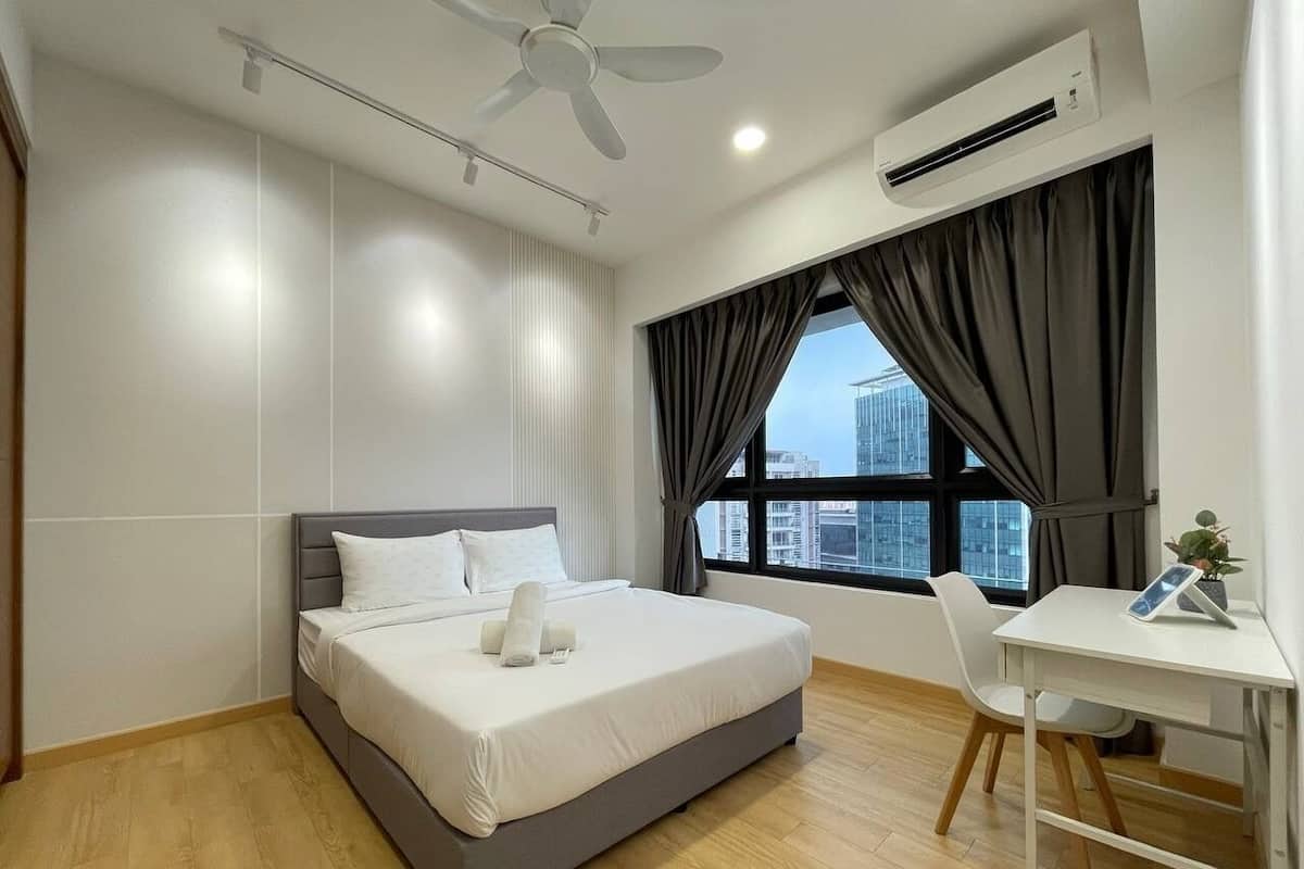 A modern hotel room with a bed, a desk, and a window with curtains.