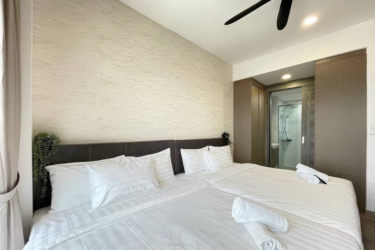A large bed with white linens, a dark headboard, and a ceiling fan.