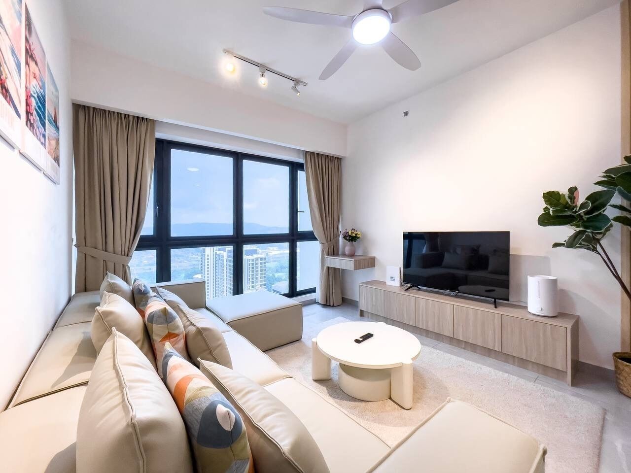 Una sala de estar moderna con un sofá, una mesa de centro, un televisor y un ventanal con vistas a la ciudad.