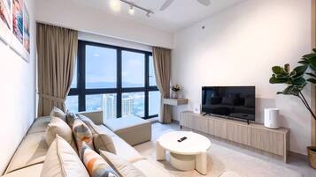 Una sala de estar moderna con un sofá, una mesa de centro, un televisor y un ventanal con vistas a la ciudad.