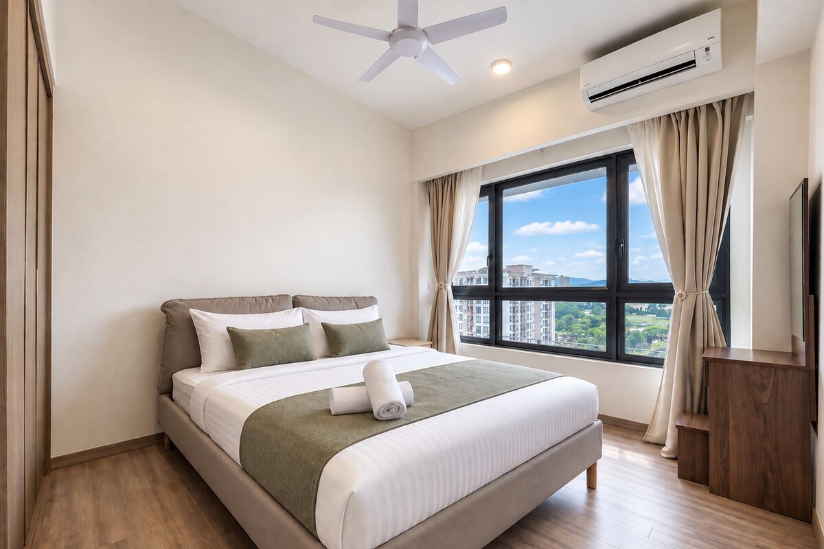 Een hotelkamer met een bed, een plafondventilator, een airconditioning en een raam met gordijnen, met uitzicht op gebouwen.