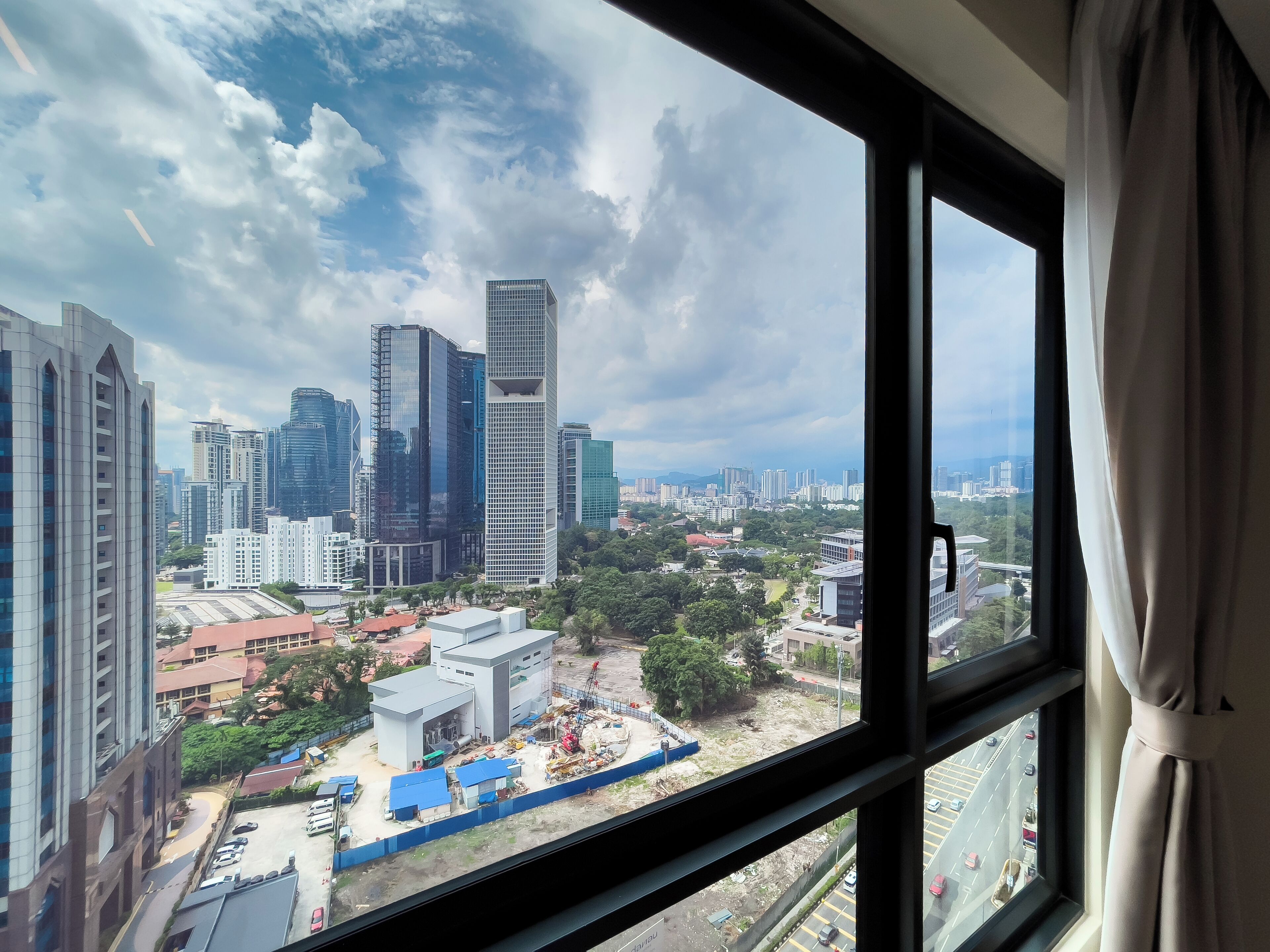 A view from a window overlooking a cityscape with modern buildings and a construction site.