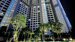 A high-rise hotel with multiple floors, a pool area in the foreground, and palm trees.
