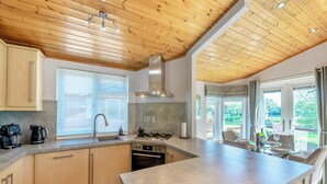 A modern kitchen with wooden cabinets, a built-in oven, and a large island.