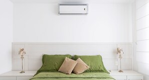 A room with a bed, a wall-mounted air conditioner, and two bedside lamps.