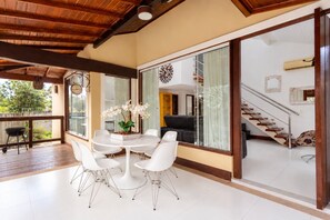 Amplia sala de estar con una mesa redonda, sillas blancas y vista al balcón exterior.