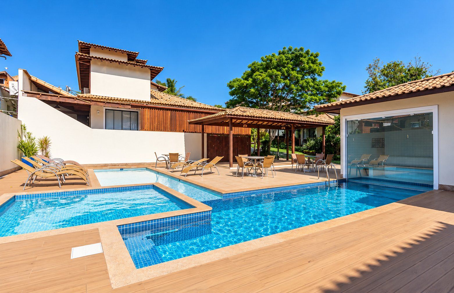 Une piscine avec des chaises longues et un espace patio couvert.
