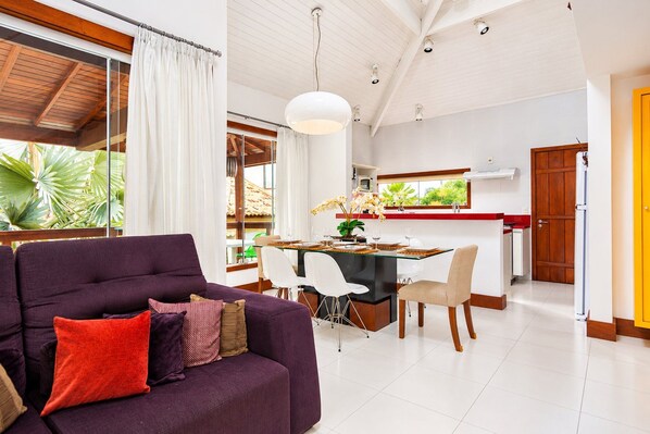 A modern living room with a purple sofa, dining area, and kitchen.